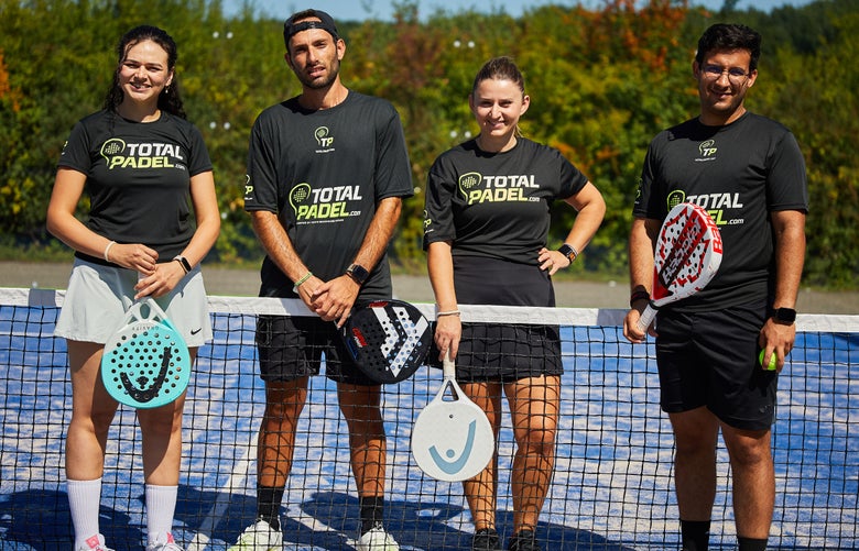 4 padel players standing at the net