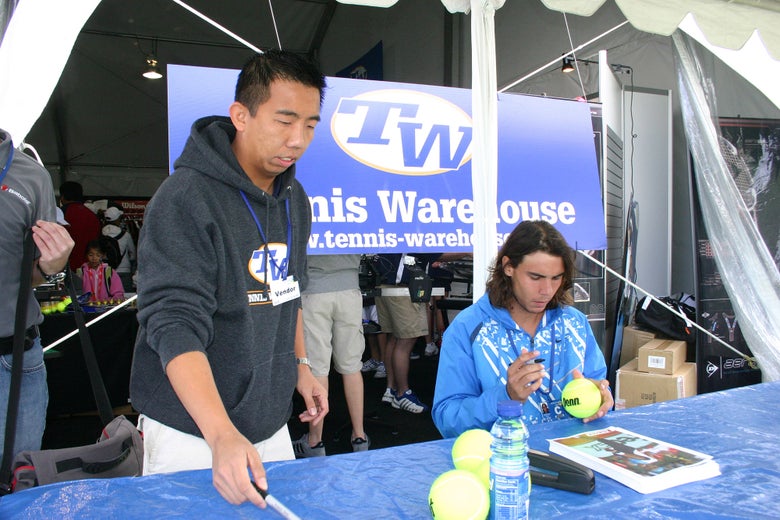 Tennis Warehouse's Jason Huang assists Rafa as he signs autographs for his fans.